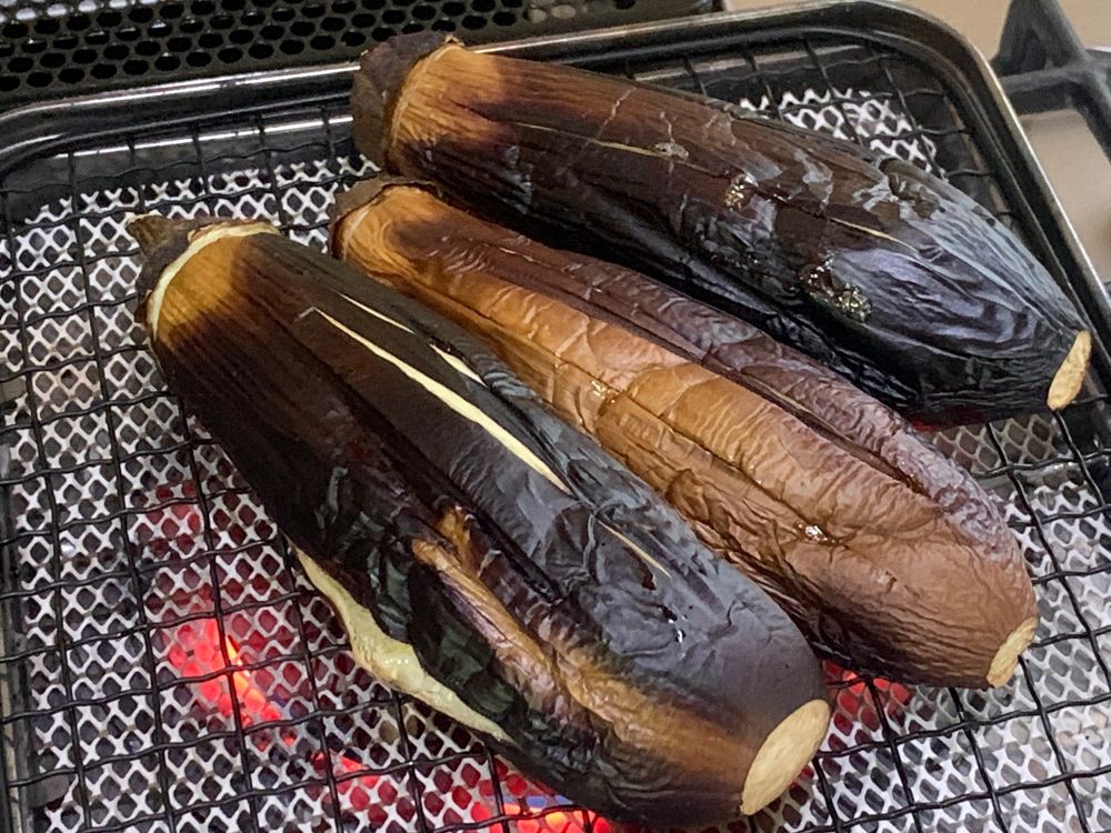 網の上になすをのせて中火で真っ黒になるまで10分ほど焼く。あら熱をとってからトングなどを使って皮をむく。