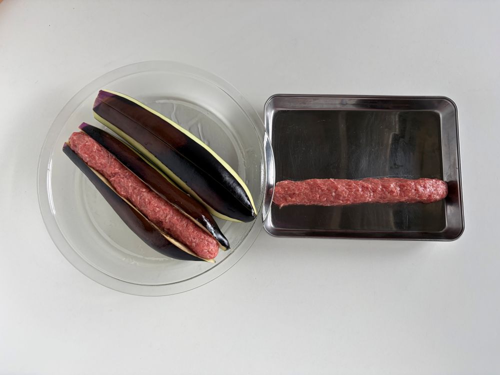 ボウルに牛豚ひき肉を入れ、(a)を加えてよくもんで混ぜる。2等分に分け、ソーセージのように細長く成形し、②のなすに挟んでラップをかけ、電子レンジ(500W)で2分30秒加熱する。