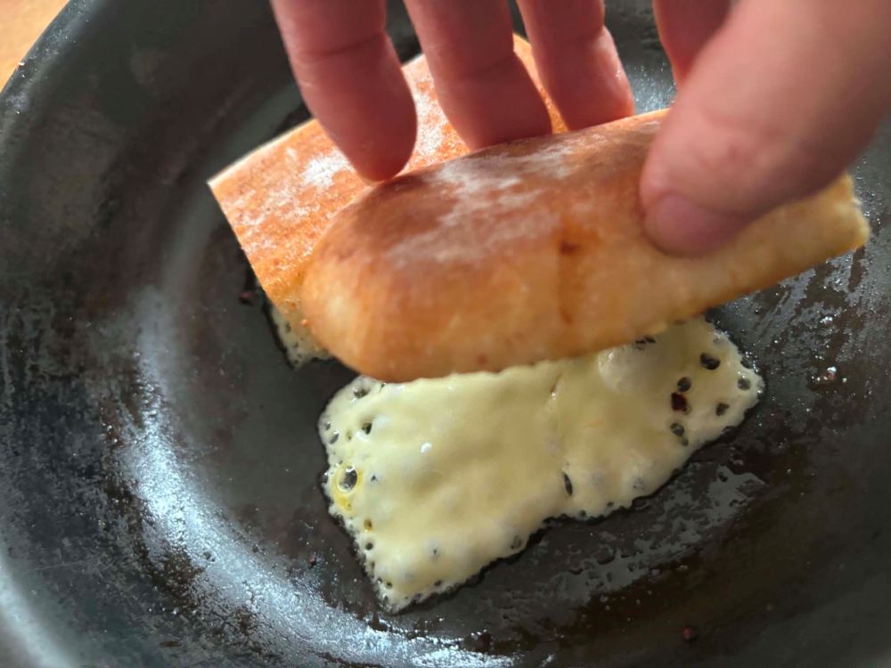 同じフライパンでパンを両面焼いてとり置く。スライスチーズを4等分にし、フライパンにのせて弱火にかけ、溶けてきたらパンでこすりとる。